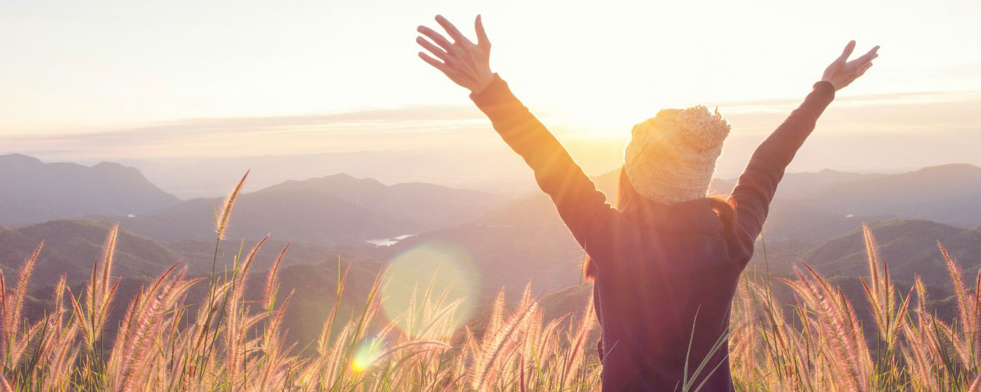 Woman with raised arms in wheat field